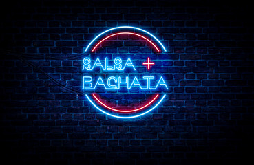 Salsa and Bachata written on a red and blue neon sign, with a brick wall in the background.