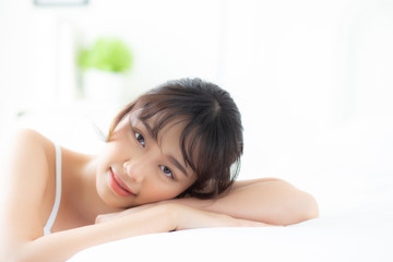 Lifestyle beautiful portrait young asian woman relax lying sleep and smile while wake up with sunrise at morning, girl with happy and fun in the bedroom, health and wellness concept.