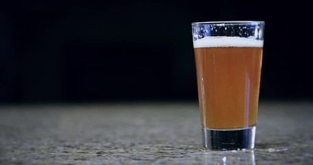 Close up of a pint of beer sliding on a bar in slow motion