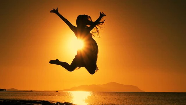 silhouette of girl jumping at sunrise on the beach
