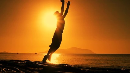 silhouette of boy jumping at sunrise on beach