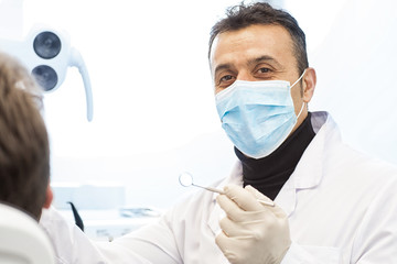 Naklejka premium Mature male dentist working with his patient
