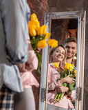 Cheerful beaming couple smiling while looking into mirror