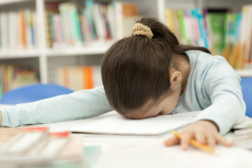 Adorable little girl studying at the library
