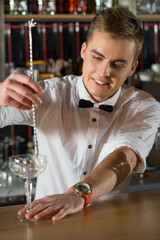 Impossible to forget. Vertical shot of a handsome bartender making drink smiling.