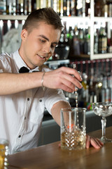 Example of hospitality. Attractive young bartender making a drink smiling.