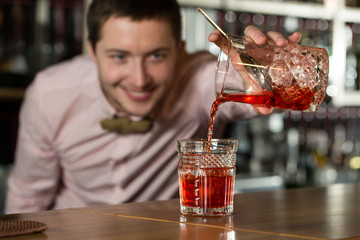 Detail orientation.  Horizontal shot of calm bartender making drinks attentively.