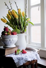 Tulips on a table in a living room. Champagne with strawberries.