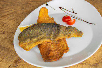 Breaded tenderloin of trout garnished with cherry tomato and dressing