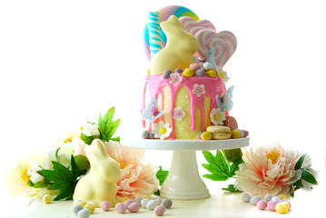 On-trend Easter theme candy land drip cake decorated with lollipops, candy eggs and white chocolate...