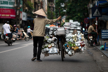 A vietnamese seller with a bike full of porcelain goods for sale in a street of Hanoi, Vietnam. Street Vendor on bicycle.
