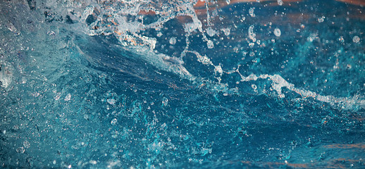 Splash of water or drops on a colored background. The concept of ecology, cleanliness, recreation, travel. Water in motion, selective focus. Banner