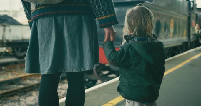 Mother and toddler on platform watching the steam train pull in to station