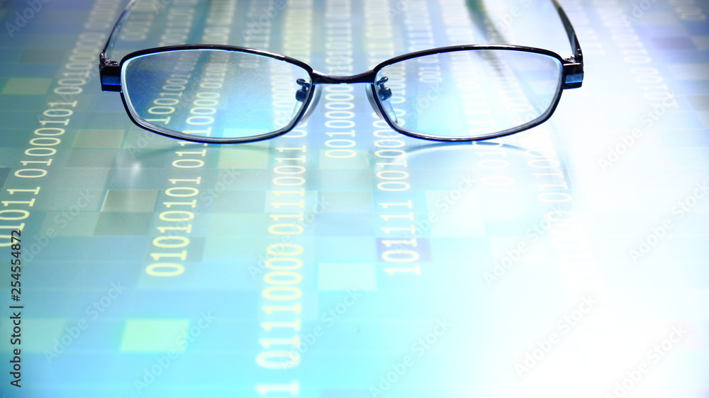 Poster reading data in digital age. glasses and flowing binary code matrix. shallow depth of field image of glasses on display panel. multiple lines of blue code moving under glasses.
