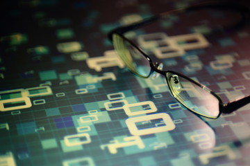 big data analysis. glasses placed on a LED digital panel display white light one and zero binary text number in moving motion pattern. modern technology blue block grid pattern backgrounds