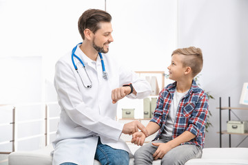 Obraz premium Doctor checking little boy's pulse with fingers in hospital