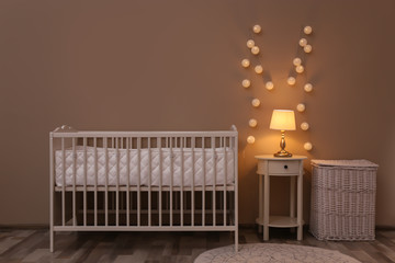 Nursery room interior with comfortable bed and fairy lights
