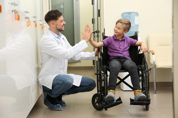 Doctor and little child in wheelchair at hospital