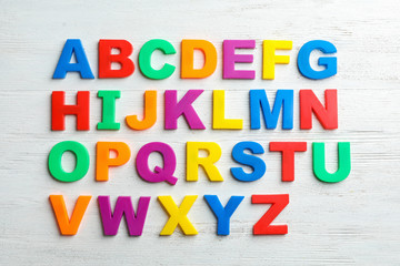 Plastic magnetic letters on wooden background, top view. Alphabetical order