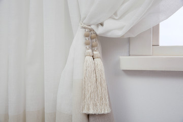 Elegant window curtain with tieback in room, closeup