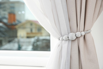 Draped window curtains with tieback in room, space for text. Home interior