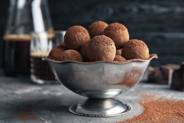 Bowl with tasty chocolate truffles on grey table