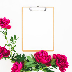 Floral composition made of red peony flowers and clipboard with paper on white background. Flat lay, top view.