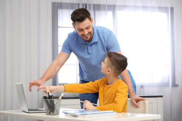 Dad helping his son with homework in room