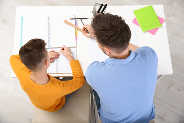 Dad helping his son with homework in room, above view