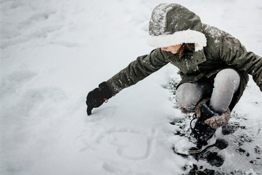 Young girl design a heart on the snow In A Snowstorm