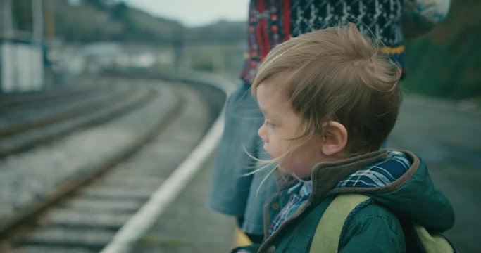 Little toddler waiting for the train with his mother on the platform