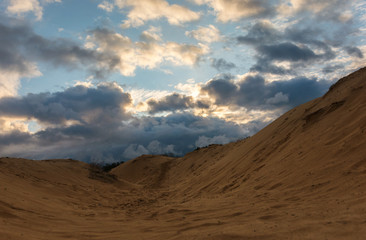 Fototapeta na wymiar volumetric clouds on a background of sandy desert at sunset