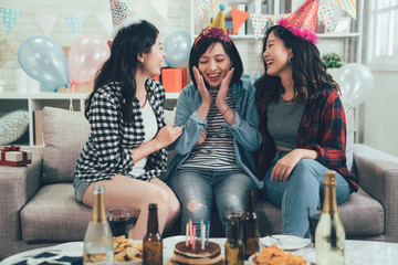 Outgoing friends giving cake with candles to cheerful girl. group of asian ladies relaxing sitting...