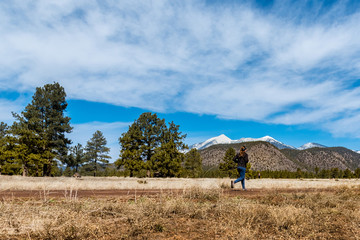 wide angle scene of female runner in flagstaff with the San Fransisco peaks in the distance.