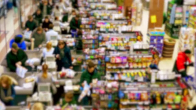 Cashier at supermarket / Retail checkout / Paying groceries. Unrecognizable buyers with carts move in queues to pay for purchases at the supermarket cashier.