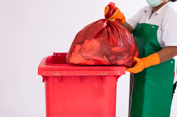 A woman worker holding red garbage bag into recycle bin.Maid and infection waste bin at the indoor...