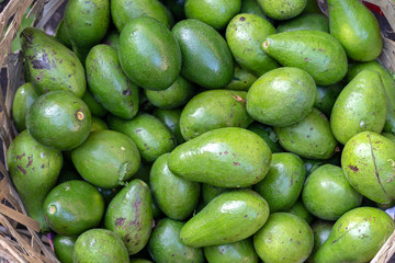 Green avocado on the bamboo or wooden basket in traditional street market in Ubud, Bali, Indonesia , closeup