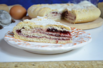 Homemade pie with cherry berries, cup of tea and fork on white wooden table. with ingredients for cooking, cinnamon, anise, icing sugar, topping. homemade baking. copy space. Top view.