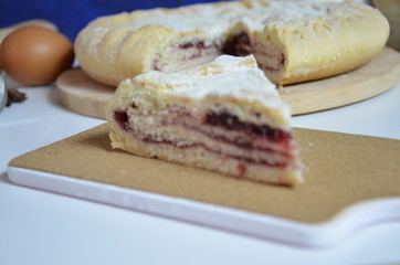 Homemade pie with cherry berries, cup of tea and fork on white wooden table. with ingredients for cooking, cinnamon, anise, icing sugar, topping. homemade baking. copy space. Top view.