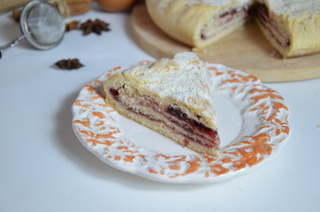 Homemade pie with cherry berries, cup of tea and fork on white wooden table. with ingredients for cooking, cinnamon, anise, icing sugar, topping. homemade baking. copy space. Top view.