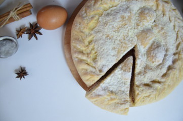 Homemade pie with cherry berries, cup of tea and fork on white wooden table. with ingredients for cooking, cinnamon, anise, icing sugar, topping. homemade baking. copy space. Top view.