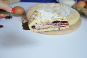 Homemade pie with cherry berries, cup of tea and fork on white wooden table. with ingredients for cooking, cinnamon, anise, icing sugar, topping. homemade baking. copy space. Top view.