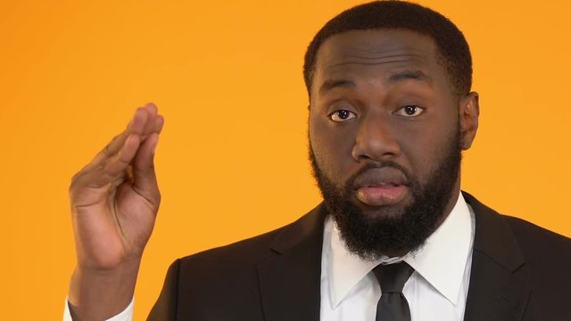 Bored Afro-American man in suit showing blah blah sign, unsuccessful negotiation