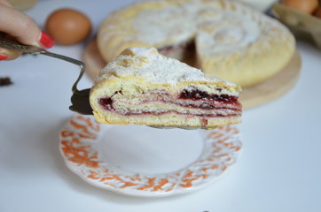 Homemade pie with cherry berries, cup of tea and fork on white wooden table. with ingredients for cooking, cinnamon, anise, icing sugar, topping. homemade baking. copy space. Top view.