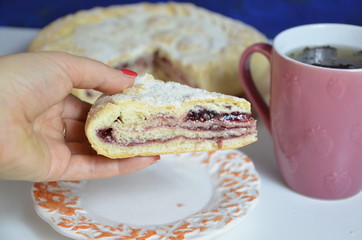 Homemade pie with cherry berries, cup of tea and fork on white wooden table. with ingredients for cooking, cinnamon, anise, icing sugar, topping. homemade baking. copy space. Top view.