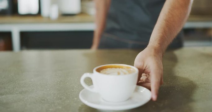 Barista presenting latte art to customer, close up cafe latte, coffee shop barista lifestyle