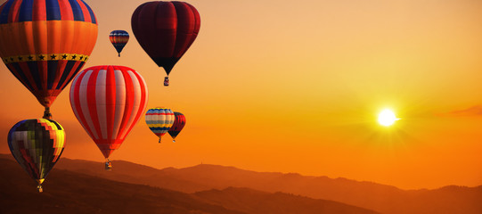 Heteluchtballon boven hoge berg bij zonsondergang