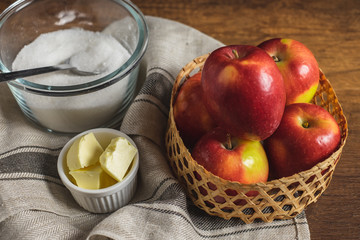 Red apple in the basket with sugar, butter, and salt. Ingredients for making apple pie or tarte tatin.