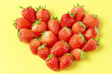 heart shaped strawberries on a yellow background, flat lay