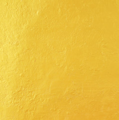 Gold paint on rough cement wall texture.